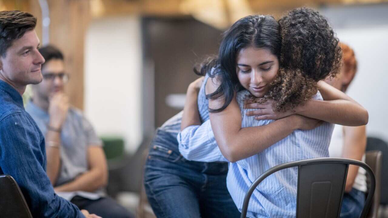 Two Women Embracing During Group Therapy