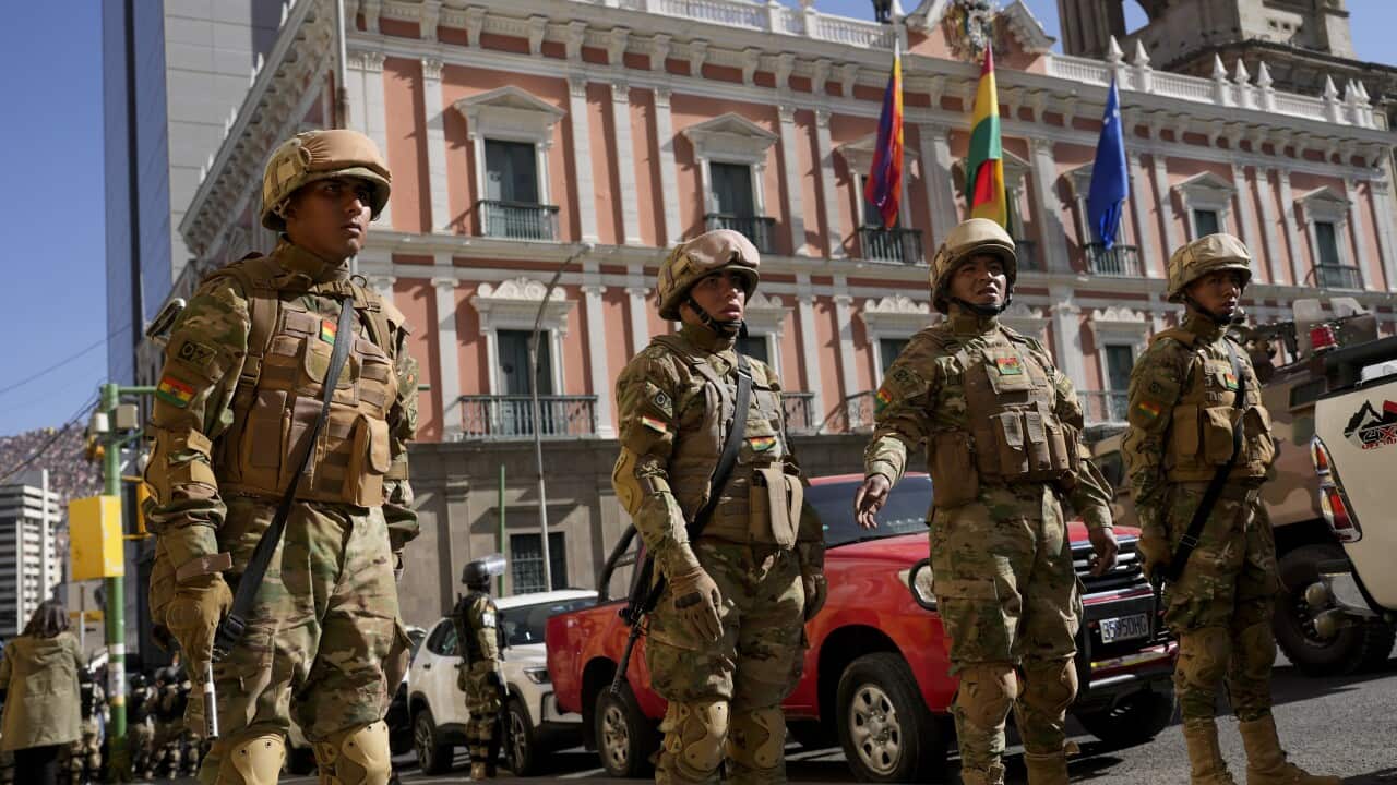A group of soldiers standing guard outside a large ornate building with flags on it.