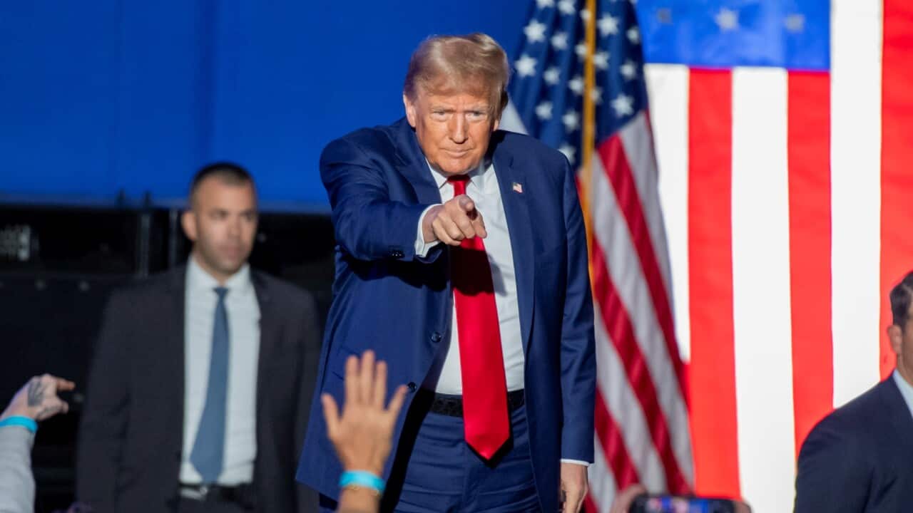 Donald Trump standing on a stage, pointing into the crowd.