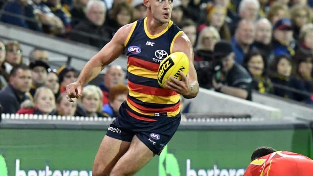 The Crows Taylor Walker runs with the ball during a match.