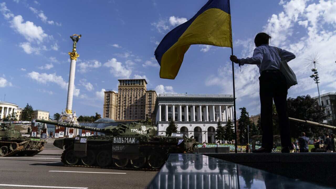 A woman holds a flag of Ukraine in Kyiv (AAP)