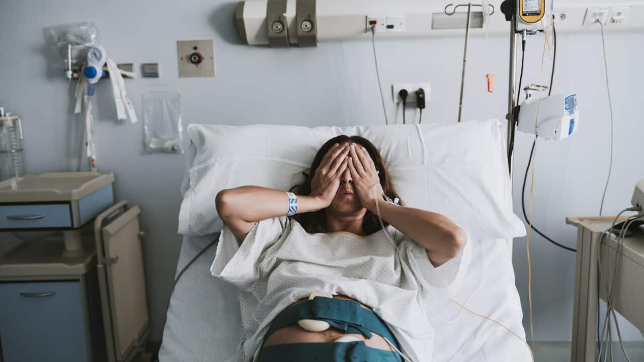 Stressed pregnant woman lying on bed in hospital