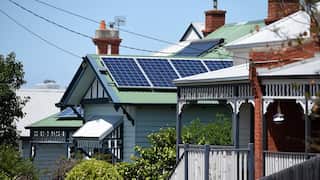 A Victorian terrace home with solar panels on the the teal roof.