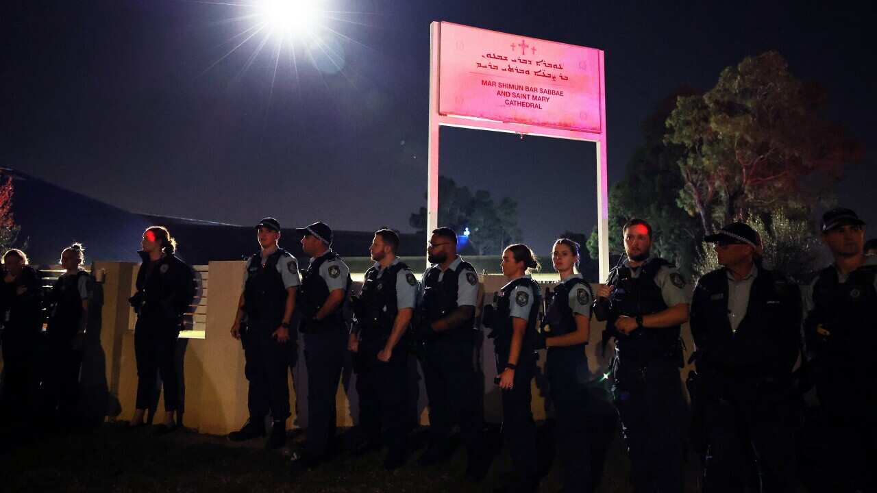 Police officers standing underneath a street light and sign for a church