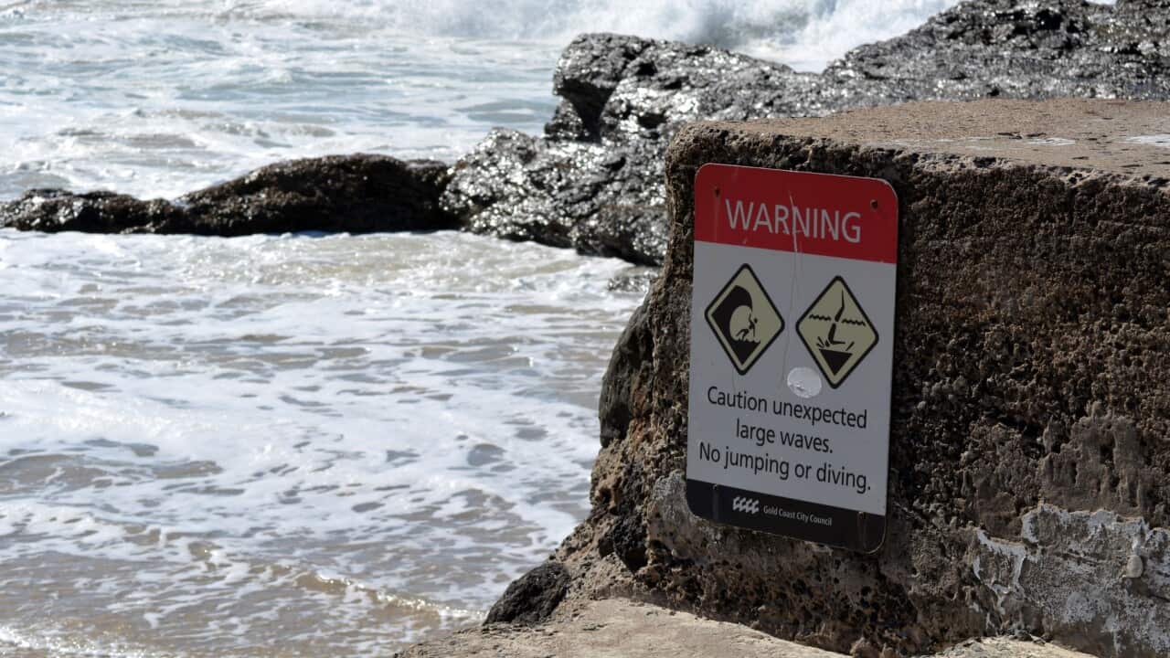 A sign warns again dangerous surf conditions at a beach