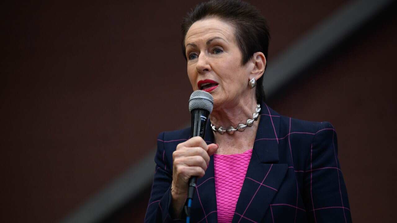 A woman standing and speaking into a microphone she is holding.
