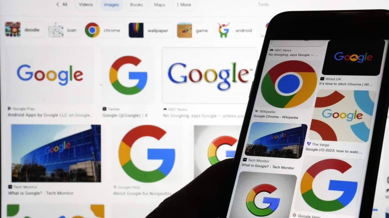 A shadow of a hand holds a phone displaying Google logos against a background also filled with Google logos.