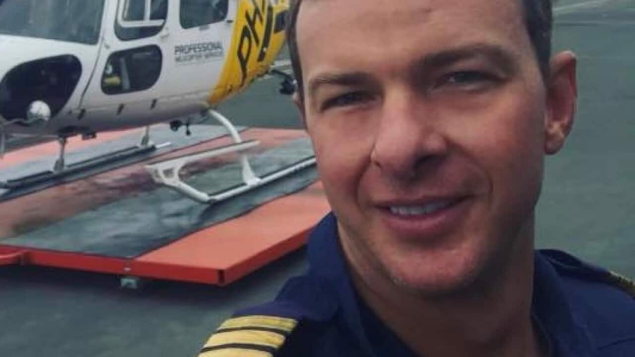 A man taking a selfie. A helicopter is behind him.