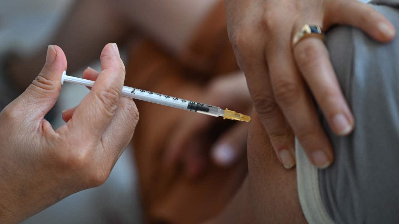 A health care worker administers a dose of a vaccine to protect against monkeypox