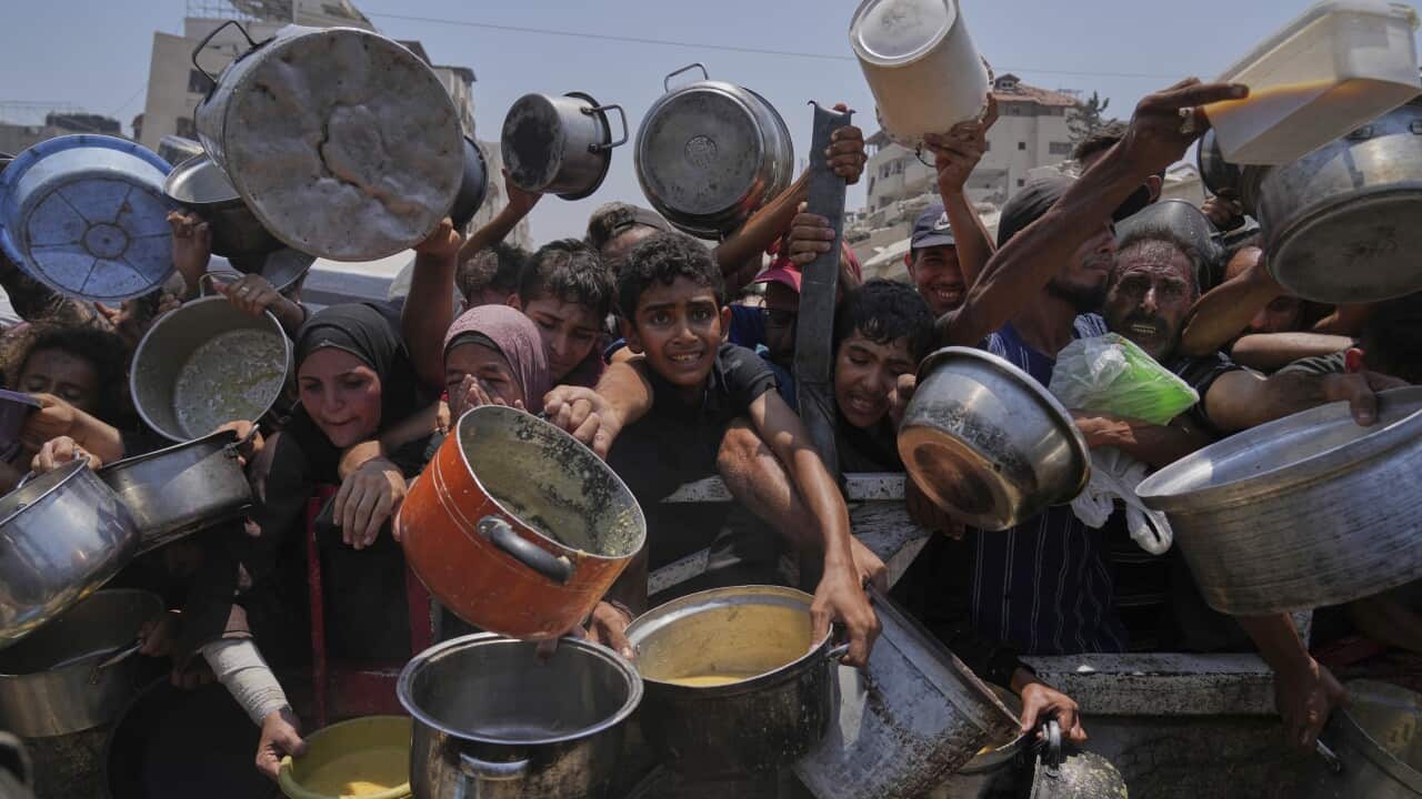 Children in a crowd scrambling with empty pots for food
