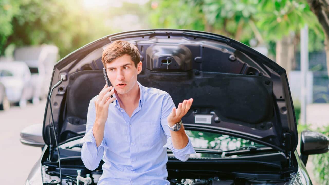 man using the phone to call an insurance company Because the car has been damaged by the engine system.