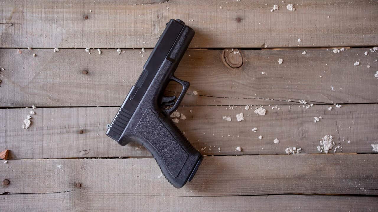 Top view of a gun on a rustic wooden surface