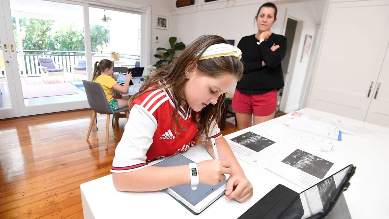 Michelle Merriman watches her daughters Audrey and Grace learn from home in Brisbane