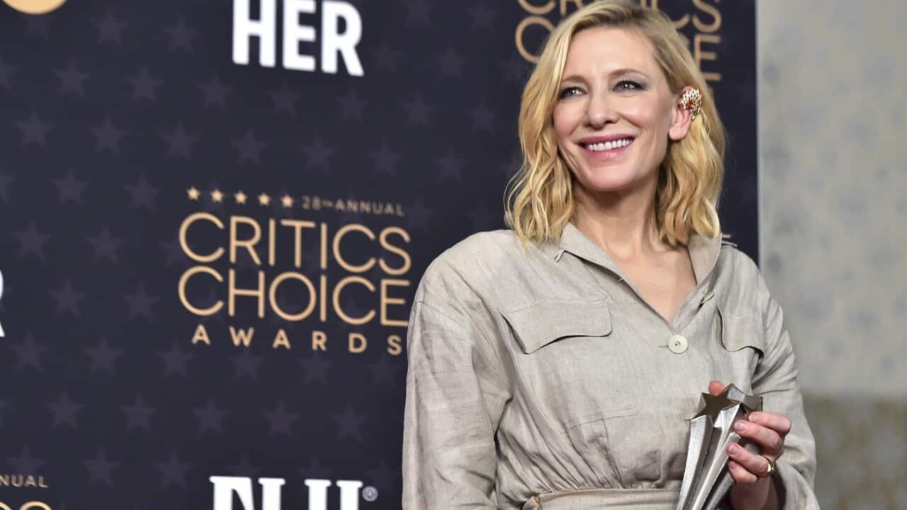 A woman stands with a trophy.