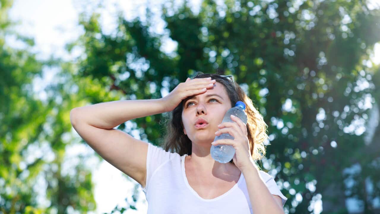 Young woman having hot flash and sweating in a warm summer day