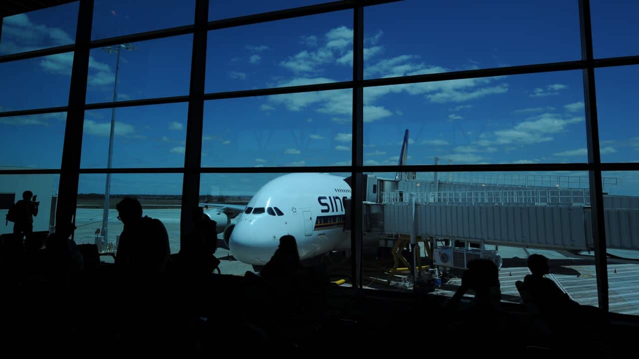 A view through a window of a Singapore Airlines place on the tarmac at an airport terminal.
