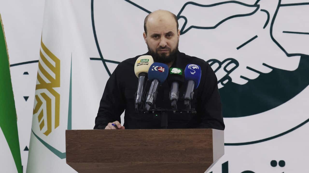 A man stands at the podium in front of media microphones.