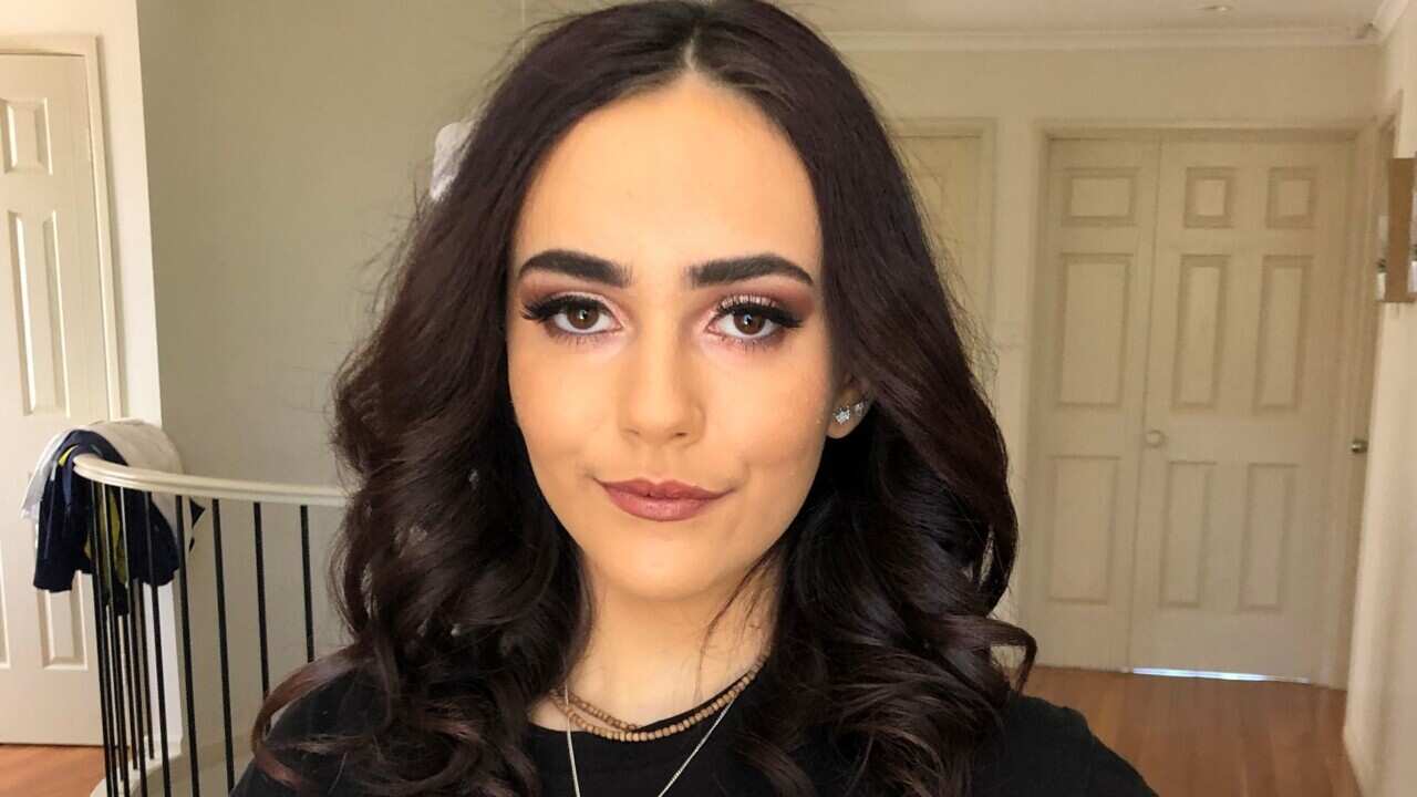 Ange Lati in a black T-shirt standing in a room of a house.