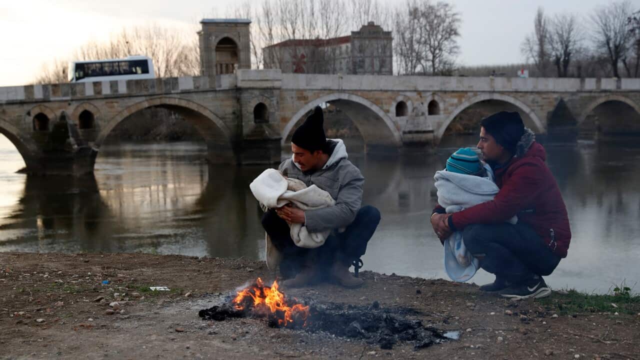 Refugees try to keep their babies warm as they wait near the Turkish-Greek border