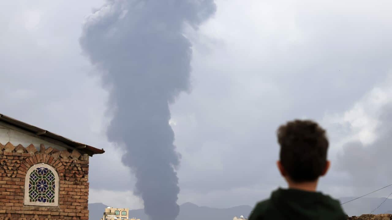 Smoke rises above buildings, and a young boy watches.
