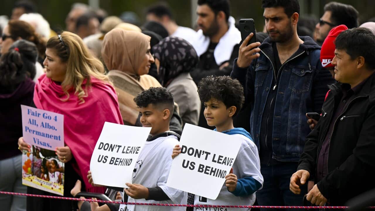 Attendants hold signs during a rally for refugee rights outside Parliament House in Canberra