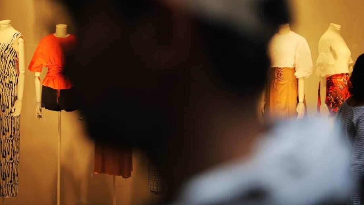 Shoppers walk past shop windows.