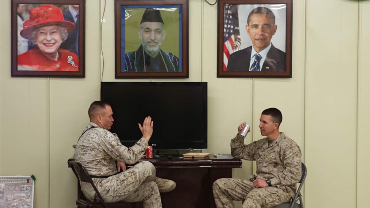 US Marines talk underneath pictures of Queen Elizabeth, Afghan President Hamid Karzai and President Barack Obama at Camp Bastion. (AFP/Getty)