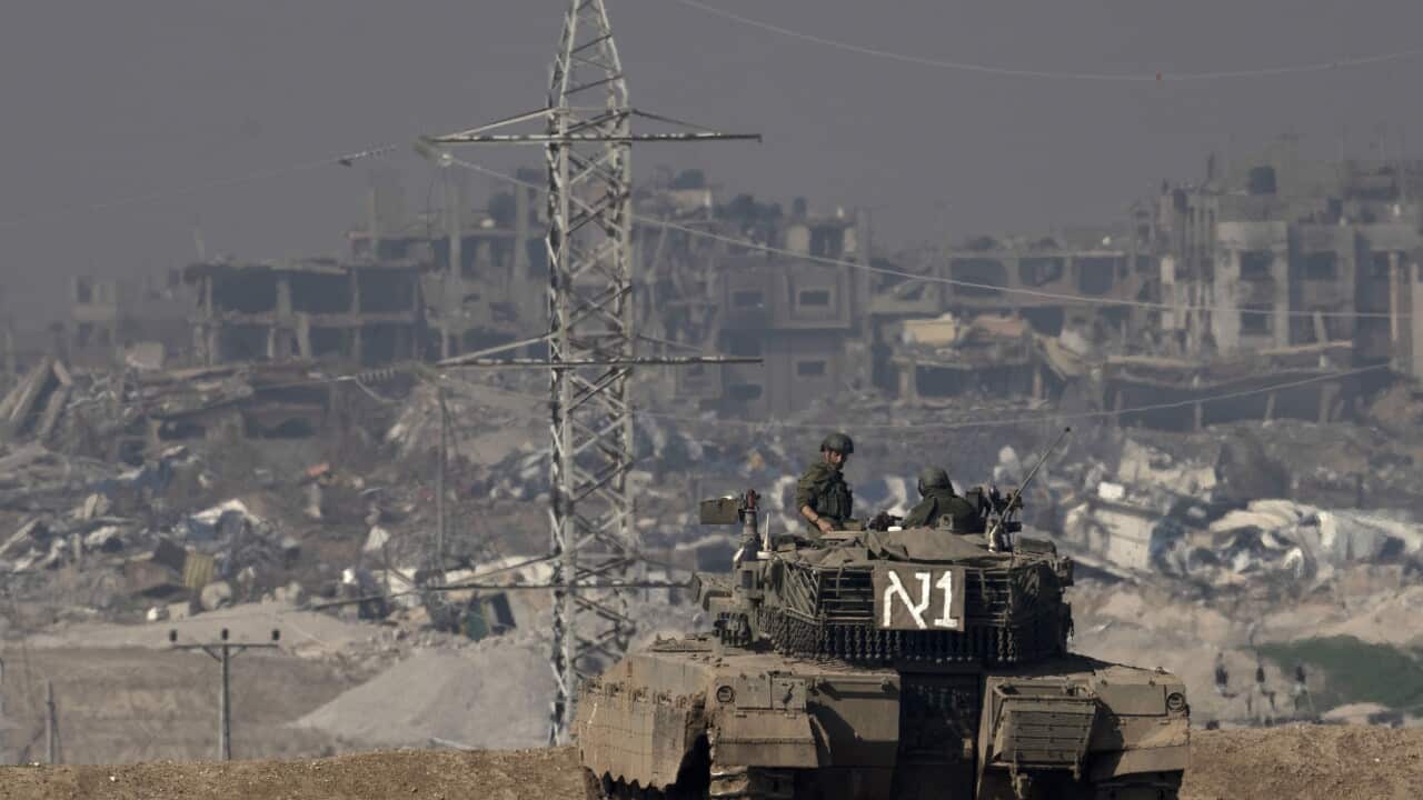 Military tank driving among rubble.