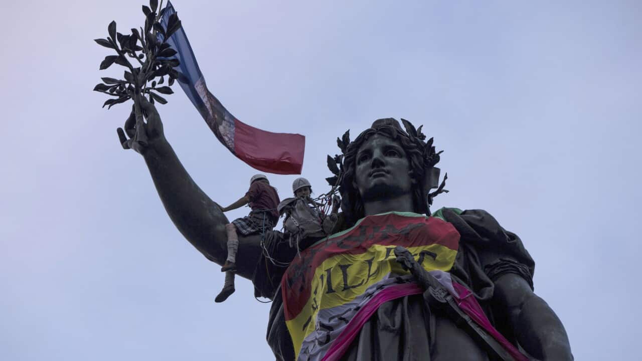 Statue of Republique plaza is decorated by flags as people gather at a protest against the far-right (AAP)