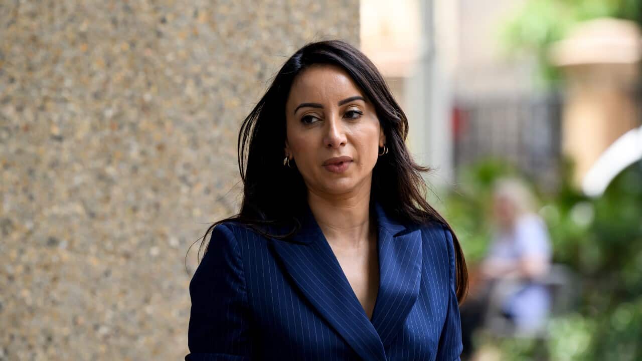 A woman in a blue blazer walking outside.