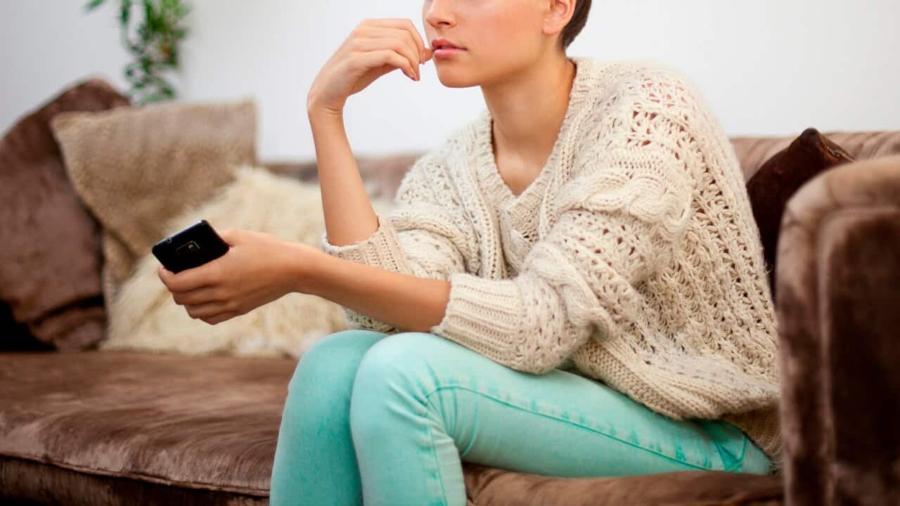 Young woman sitting on sofa with smartphone