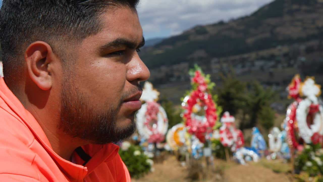 Homero Gomez Valencia looks out into the distance near a gravesite.