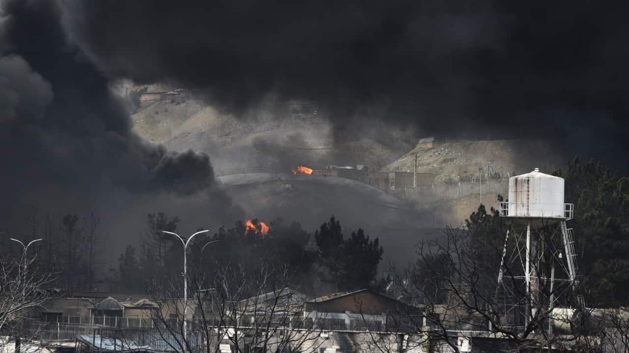 Thick black smoke surrounds buildings and oil infrastructure as several fires burn
