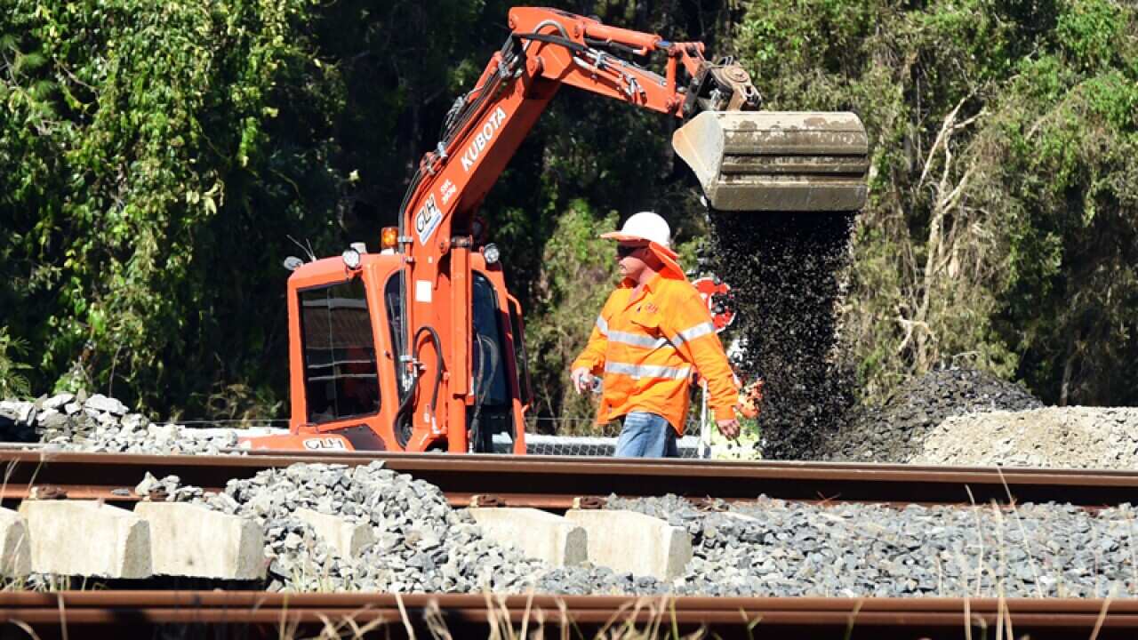 Workers repair a train line damaged in storms north of Brisbane