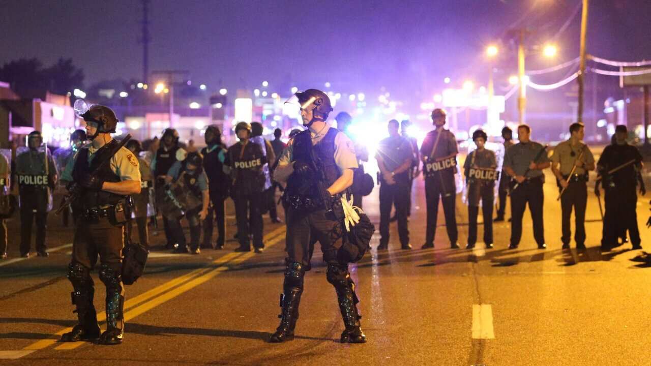Police position themselves along W. Florissant Road, in Ferguson, Missouri, USA, 10 August 2014, one day after a St. Louis police officer fatally shot unarmed 18-year-old Michael Brown. The FBI has opened an inquiry into the incident. (AAP)