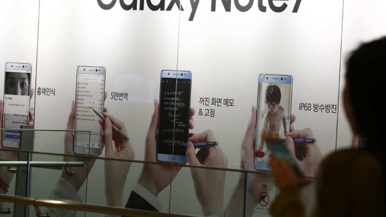 A woman walks past an ad for the Samsung Galaxy Note 7 om Seoul
