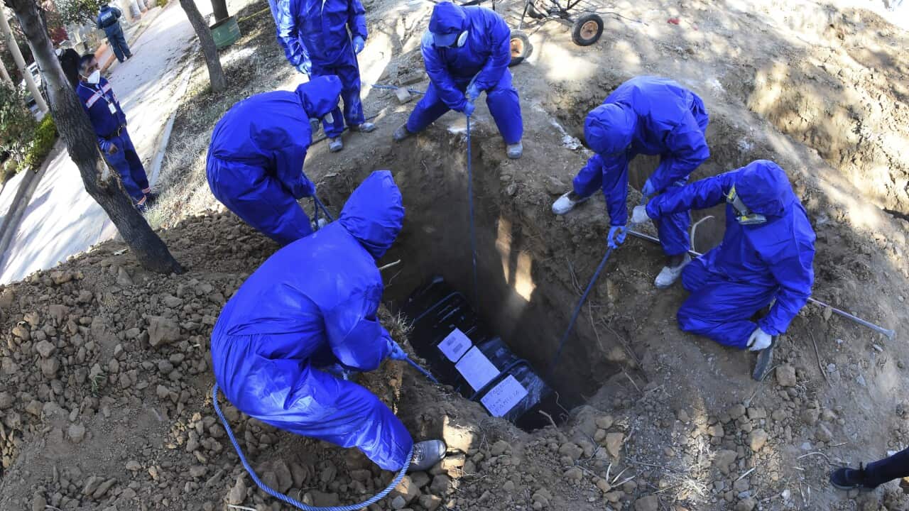 A coffin wrapped in plastic is lowered into a common grave at a cemetery in Cochabamba, Bolivia