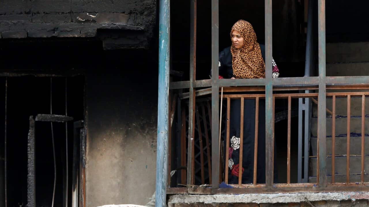 woman looking at the burnt house