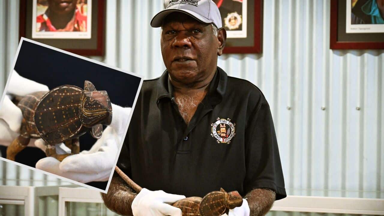 Tiwi Land Council Chairman Gibson Farmer Illortaminni holds the frilled neck lizard artefact that was carved by his grandfather.