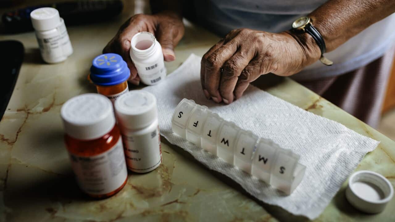 An older person sorting her medicines for the week