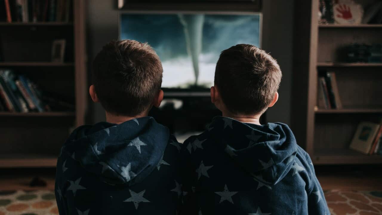 Two children watching TV together.