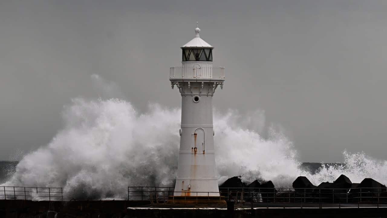 White lighthouse with crashing waves in stormy weather.