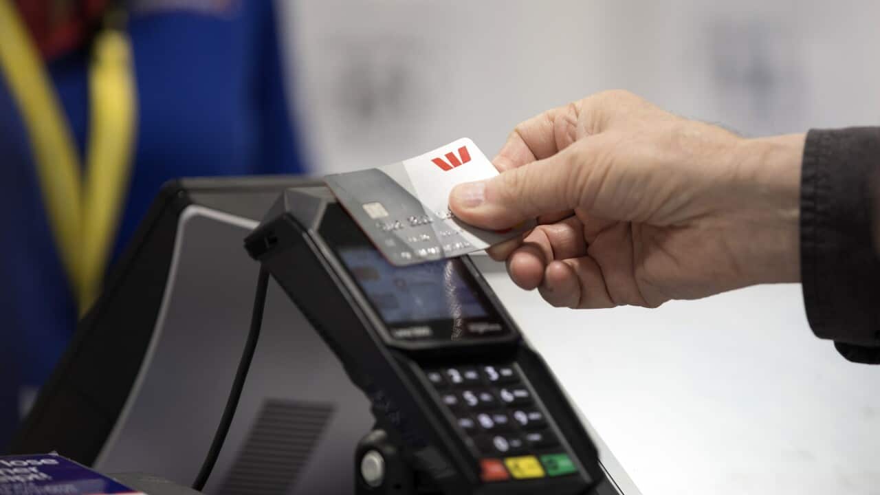 A hand tapping a credit card on a machine.