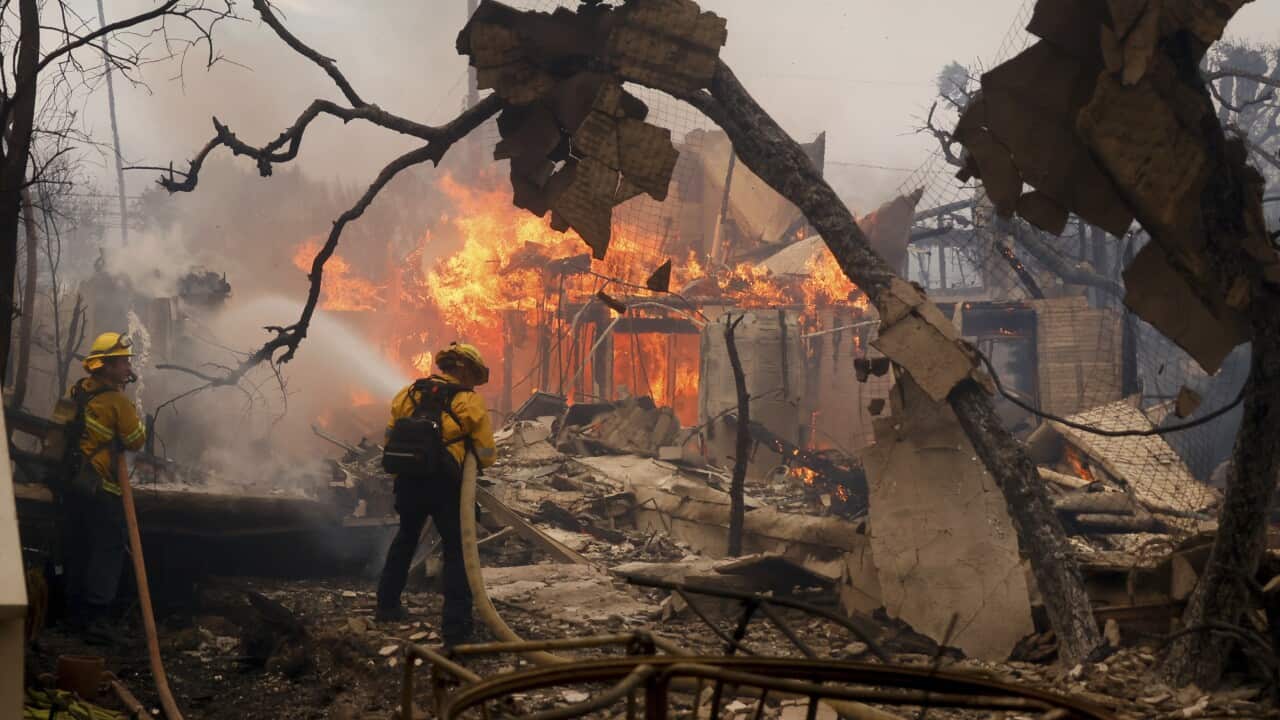 Firefighters battle the Palisades Fire as it burns in a destroyed building.