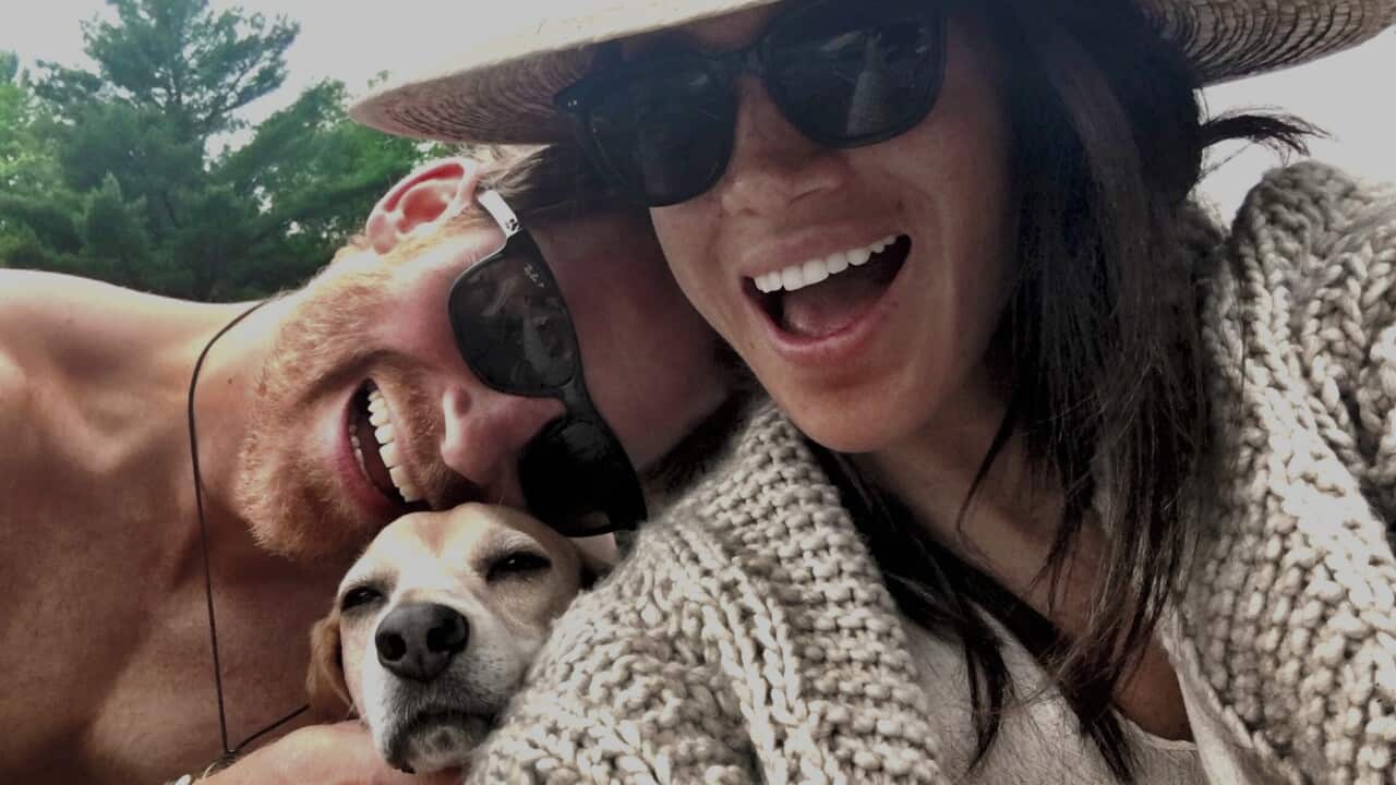 Prine Harry and Meghan Markle pse in a selfie with a dog