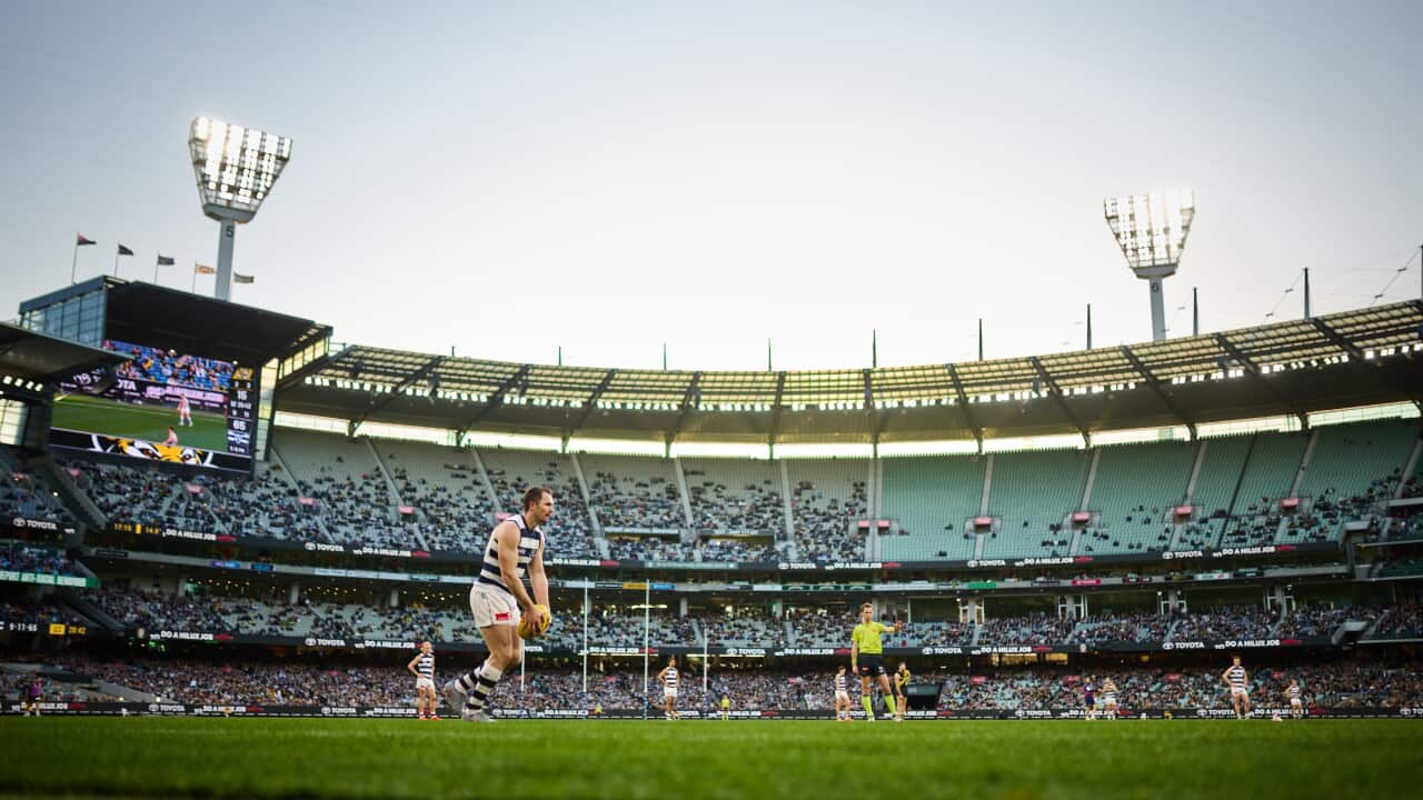 A man kicks a ball in a large stadium
