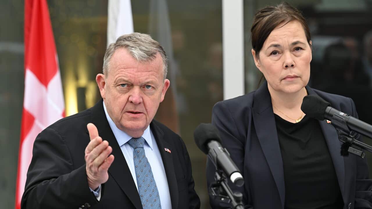 A man and a woman wearing suits are holding a press conference.