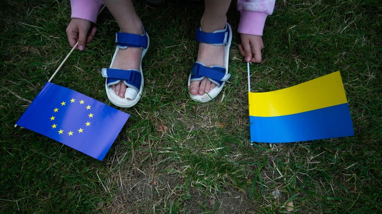 a Ukrainian girl holds both EU flag and Ukraine flag