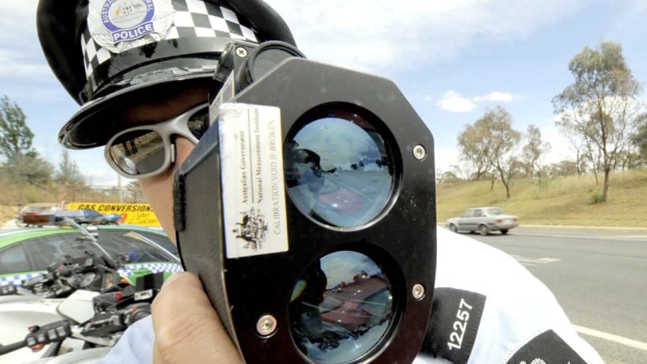 A police officer monitors traffic with radar