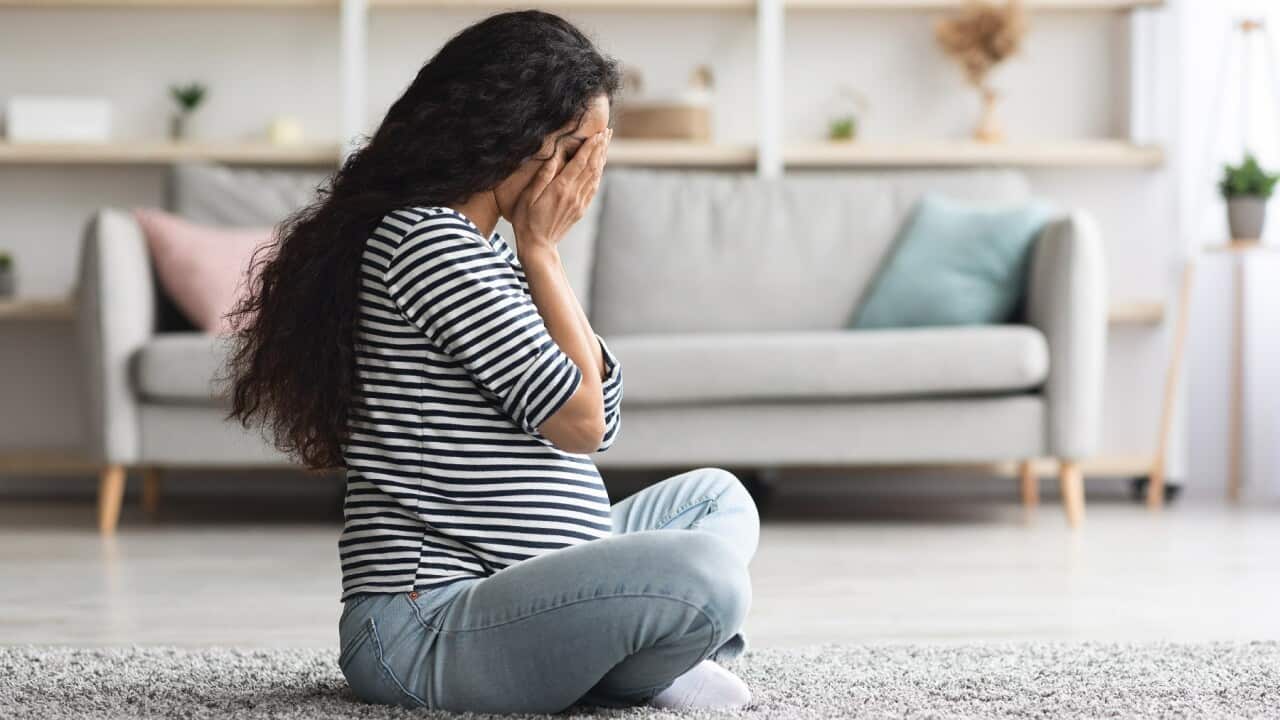 Crying pregnant woman feeling down while staying alone at home